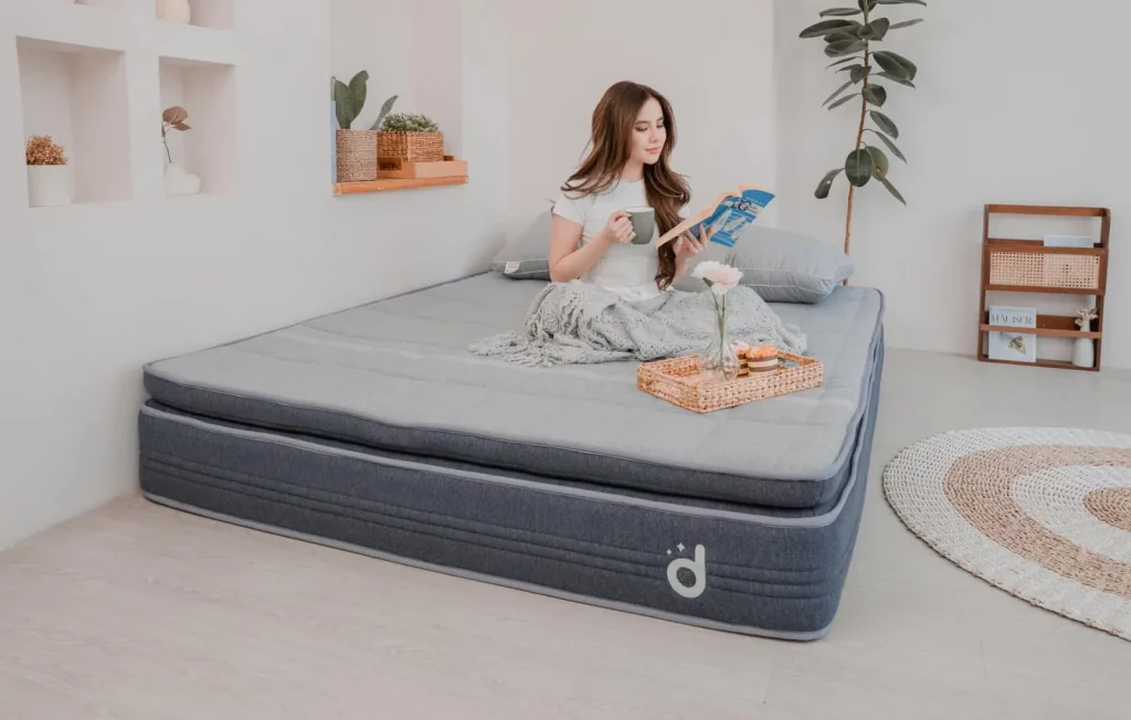 Perempuan sedang membaca di atas Domi Plush Hybrid Mattress